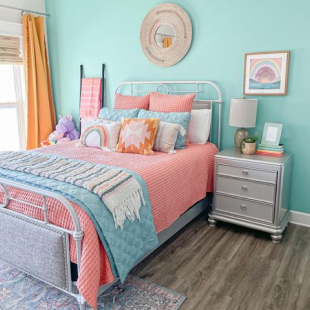 bright pastel colored bedding, with pillows and night stand in cheerful bedroom