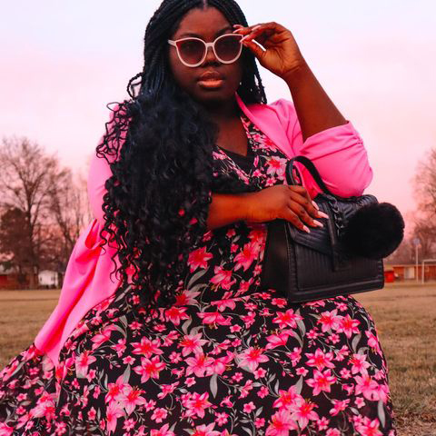 A woman wearing a budget friendly beautiful maxi dress with fuchsia color flowers and a pink Spring jacket form a Ross store