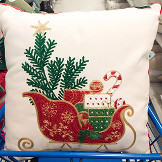 An image displaying an adorable pillow with Christmas metal sleigh car and a Christmas tree design from a Ross store