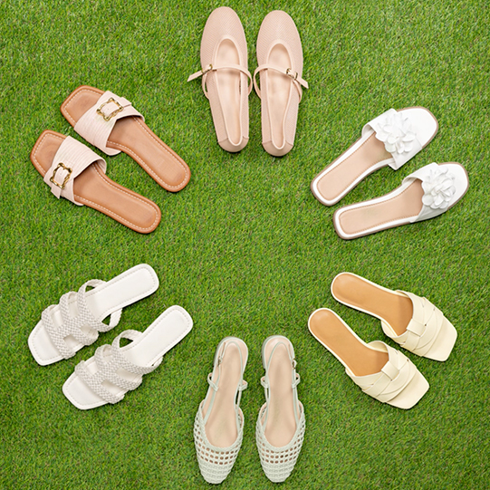 Assortment of sandals placed in a circle on grass.