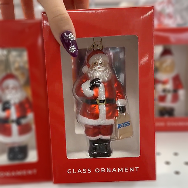 Glass Christmas ornament featuring Santa Claus in a red suit holding a shopping bag, packaged in a red box.