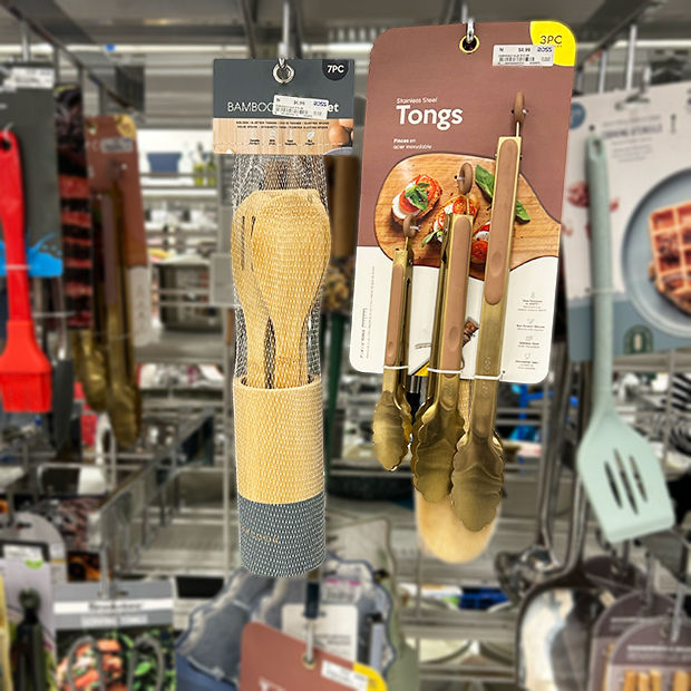 Hanging display of kitchen utensils, including a bamboo utensil set and a set of stainless steel tongs.