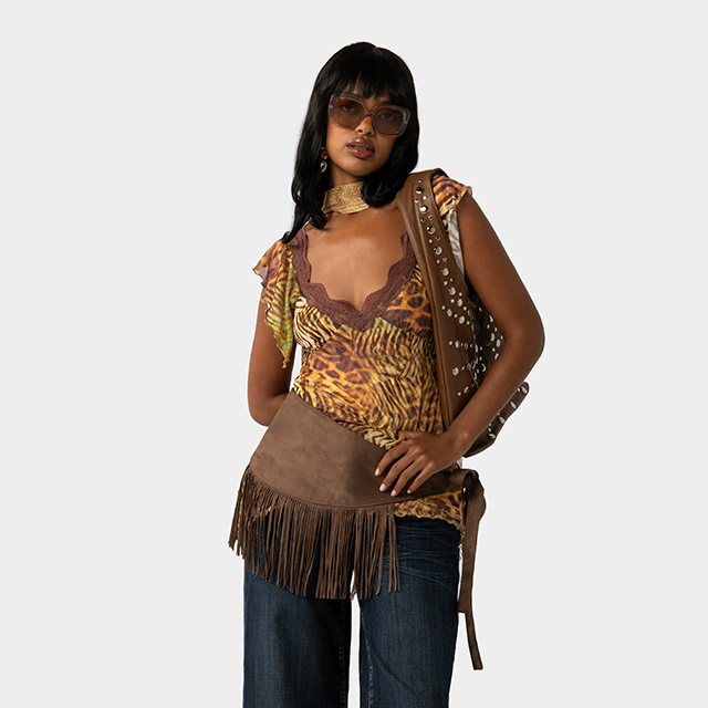 Model wearing a military-inspired olive jacket, plaid skirt, wide belt, and cream scarf, styled in a classic fall outfit against a light background.